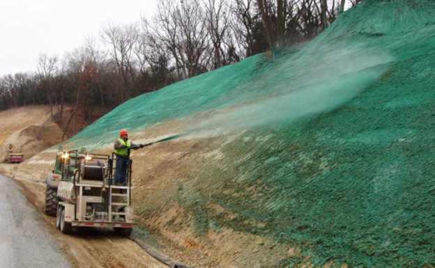 Proses hydroseeding pada lereng reklamasi menggunakan mesin hydroseeder untuk mempercepat pertumbuhan vegetasi.